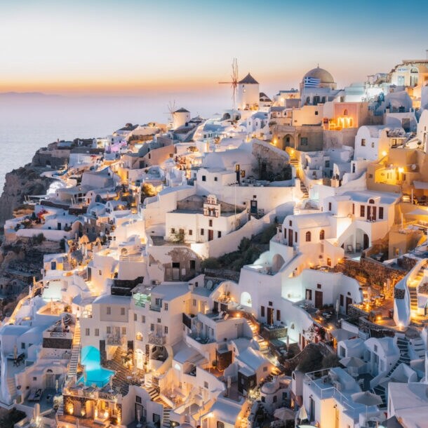 Dorf in Hanglage an einer Feldsküste mit beleuchteten weißen Häusern bei Sonnenuntergang.