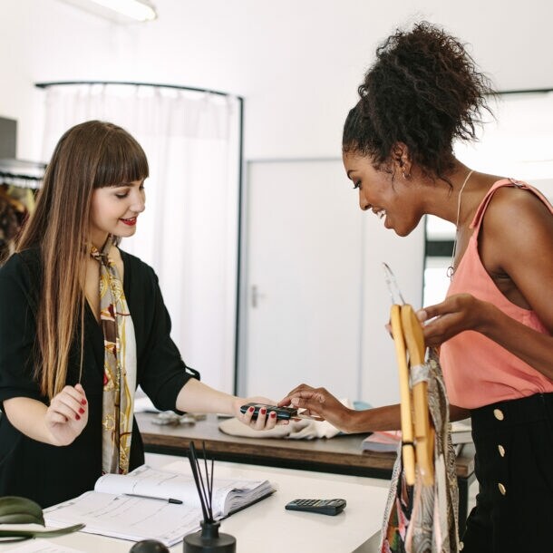 Eine junge Frau bezahlt in einer Boutique ihren Einkauf.