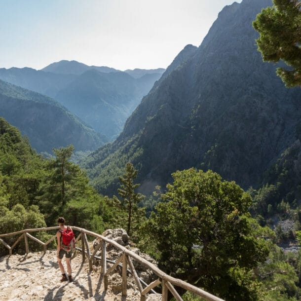 Eine Person beim Wandern in der Samaria-Schlucht auf Kreta, im Hintergrund Vegetation und Berggipfel.