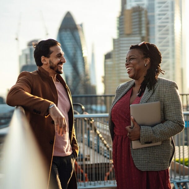 Eine Geschäftsfrau und ein Geschäftsmann unterhalten sich auf einer Dachterasse in London.