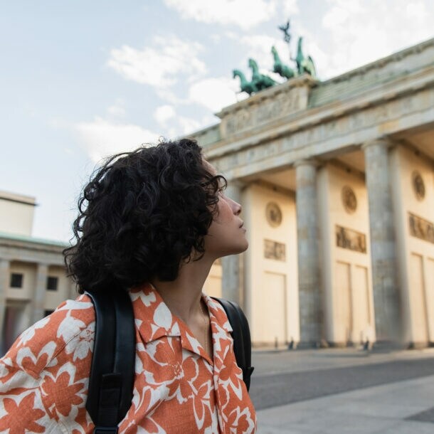 Eine junge Frau schaut auf das Brandenburger Tor.