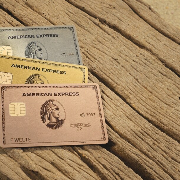 Die American Express Gold Card Rosé, die Gold Card und die Platinum Card liegen auf einer Holzfläche.