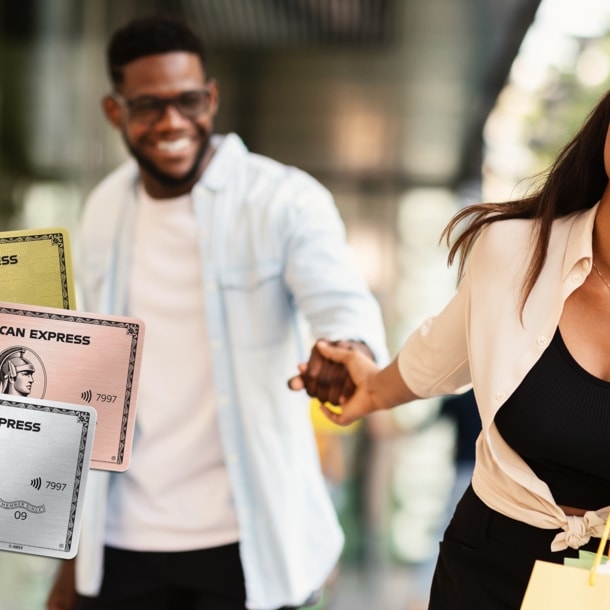 Ein Mann und eine Frau laufen Hand in Hand lachend vor einem Geschäft, im Vordergrund sieht man drei Kreditkarten von American Express.