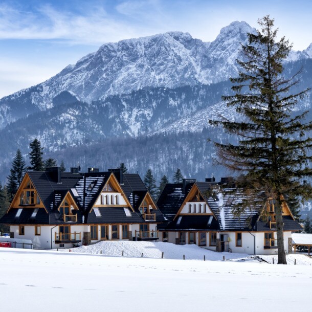 Das Dorf Kościelisko in der polnischen Tatra, im Hintergrund schneebedeckte Berge.