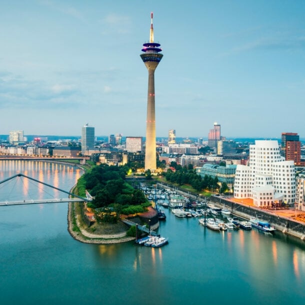 Skyline von Düsseldorf mit Fernsehturm am Hafen mit modernen Gebäuden in der Abenddämmerung.