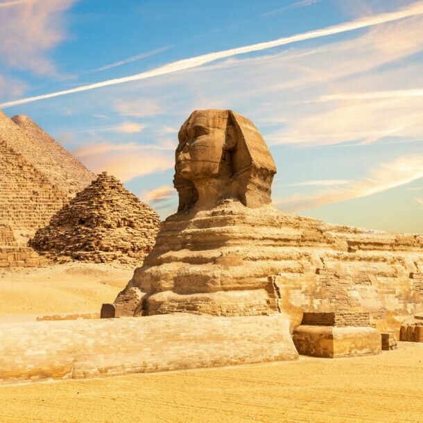 Sphinx Statue neben den Pyramiden von Gizeh in Wüstenlandschaft, im Vordergrund eine silberne Kreditkarte von American Express als Freisteller.