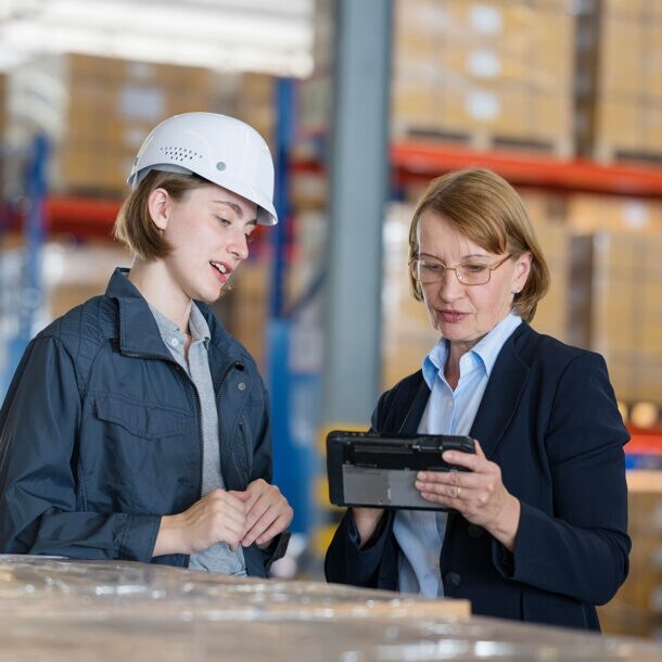 Zwei Frauen einer unterschiedlichen Generationen stehen zusammen in einem Lagerraum.
