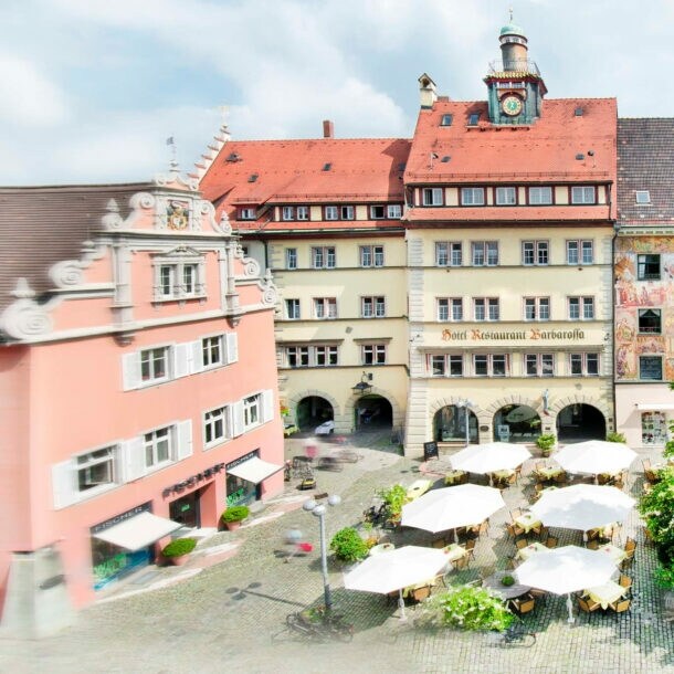 Blick auf begrünten und kopfsteingepflasterten Obermarkt mit dahinterliegender Häuserfassade mit historischem Fresko.
