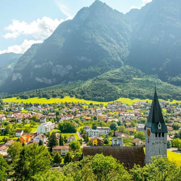 Landschaftsaufnahme eines Tals in Liechtenstein mit Kirche, vielen Häusern und Bergpanorama
