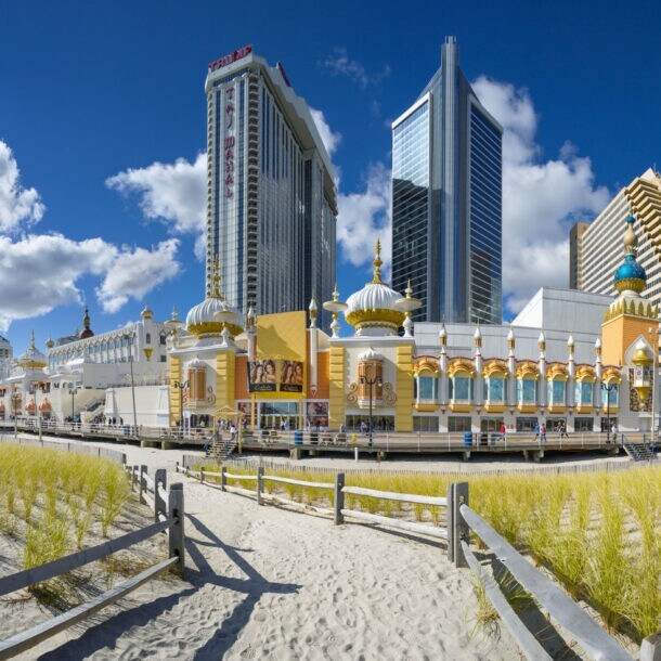 Strandpromenade mit Gebäude im orientalischen Stil vor Hochhäusern unter blauem Himmel.