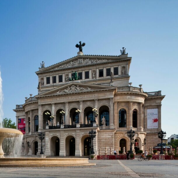 Opernplatz mit Springbrunnen und dahinterliegend das historische Gebäude der Alten Oper Frankfurt.