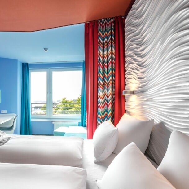 Modernes Hotelzimmer mit farbenfrohen Wänden und Strandblick.