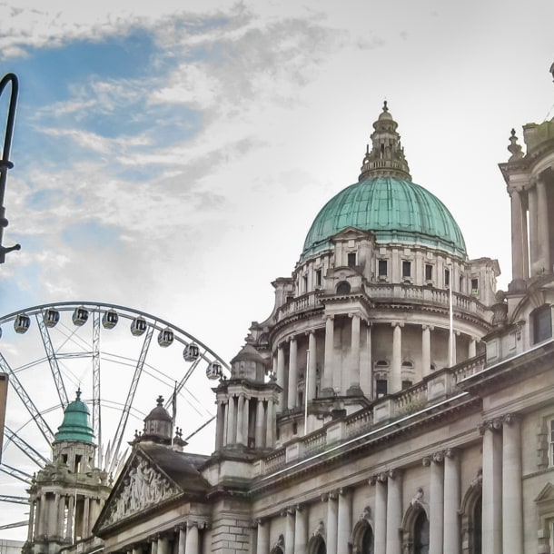 Historisches Gebäude mit grüner Kuppel und Riesenrad im Hintergrund bei Sonnenlicht