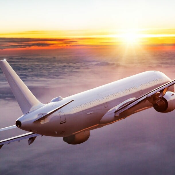 Ein geneigtes Passagierflugzeug über den Wolken bei Sonnenuntergang.