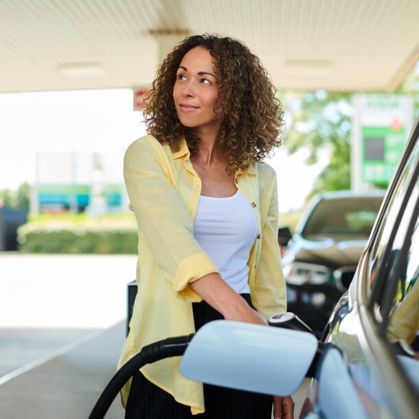 Eine Frau betankt ihr Auto an der Zapfsäule einer Tankstelle.