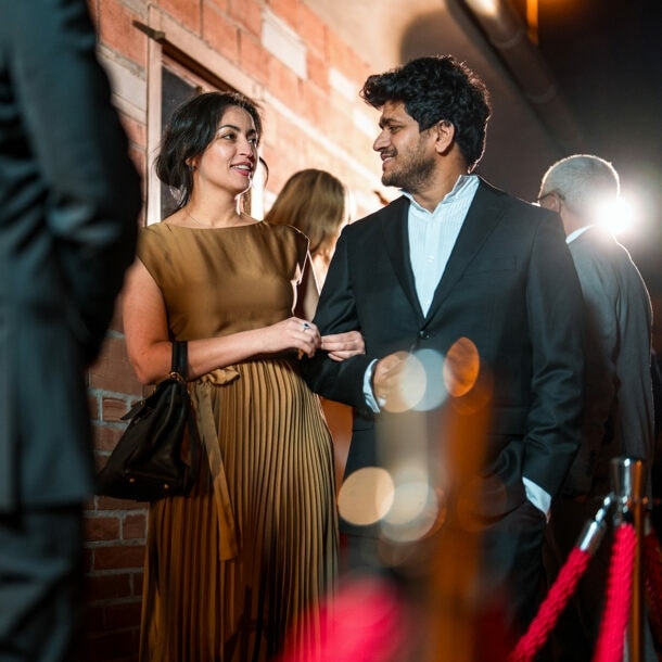 Ein glamouröses Paar steht vor dem Einlass eines exklusiven Events.