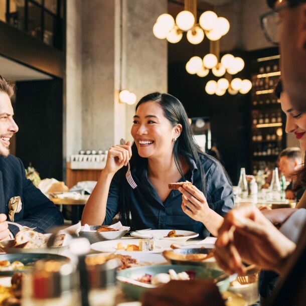 Vier fröhliche Menschen an einem Tisch im Restaurant.