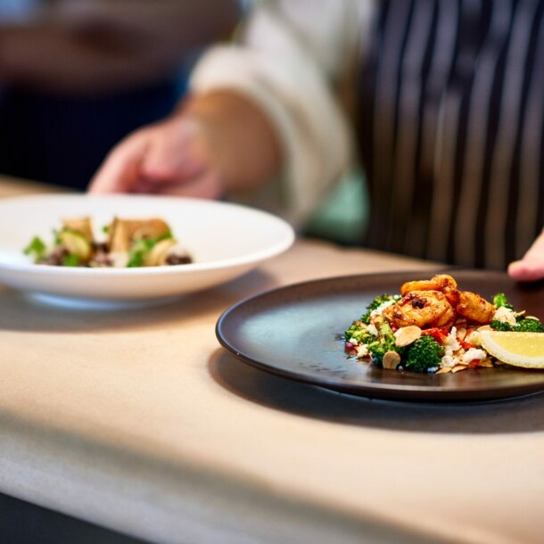 Ein Koch stellt zwei Teller mit zubereiteten Speisen auf die Theke.