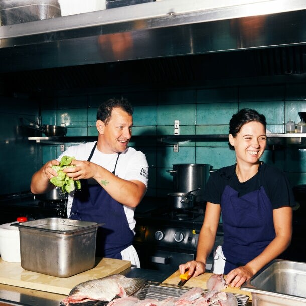 Koch und Köchin bereiten Salat und Fisch in der Restaurantküche vor.