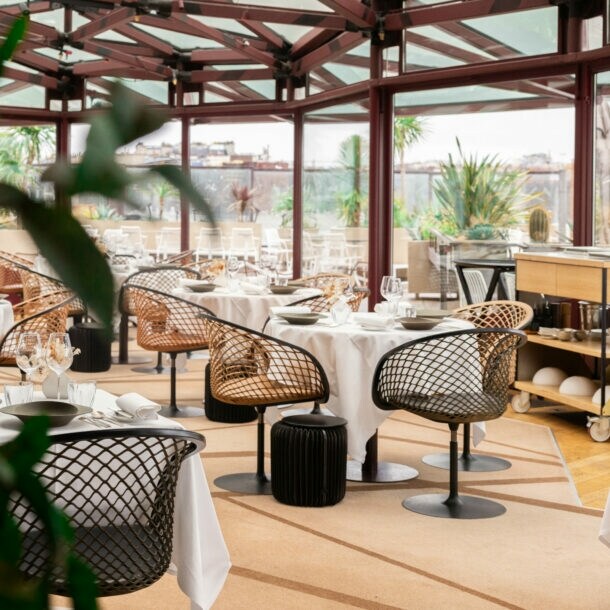 Interieur-Aufnahme eines modernen Restaurants mit gedeckten Tischen und bodentiefen Fenstern, die den Blick auf Paris freigeben.