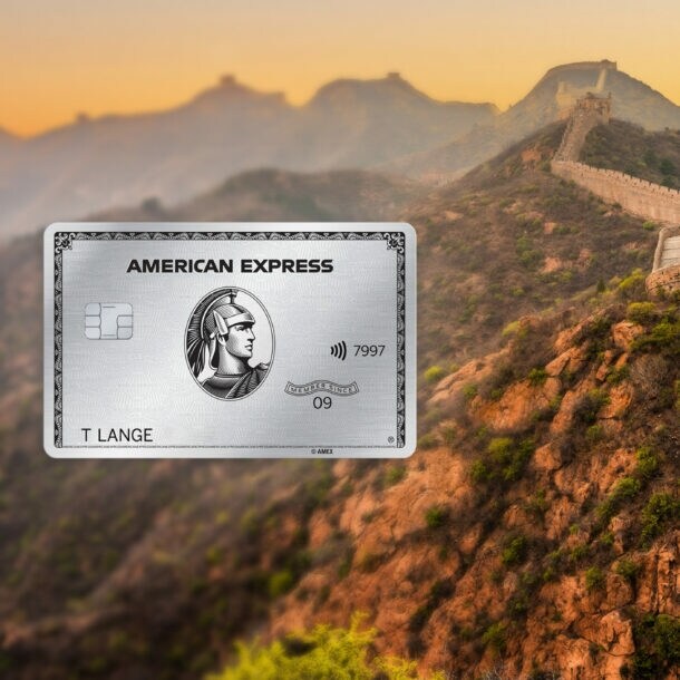Abschnitt der Chinesischen Mauer mit Wachturm in Berglandschaft bei Sonnenuntergang, im Vordergrund eine silberne Platinum Kreditkarte von American Express als Freisteller.