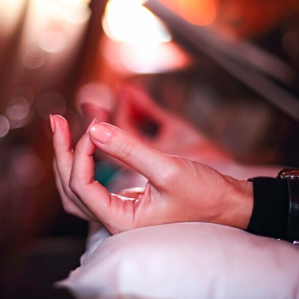Hand in Meditationshaltung auf einem Kissen in einem Flugzeugsitz