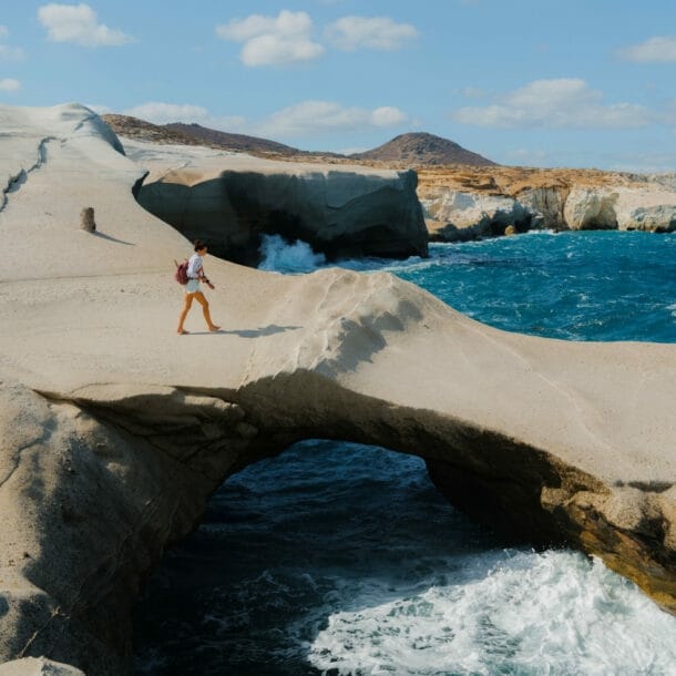 Eine Frau läuft auf einer bizarren Felsformation aus Vulkangestein am Meer.