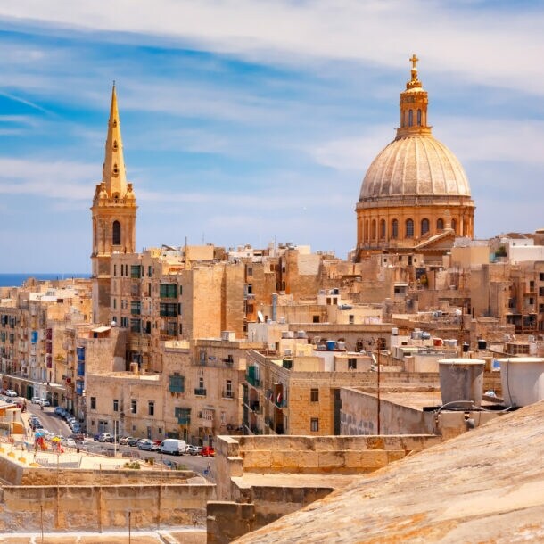 Blick auf die historische Skyline von Valletta, Malta, mit der Kuppel der St. Pauls Kathedrale und dem Meer im Hintergrund.