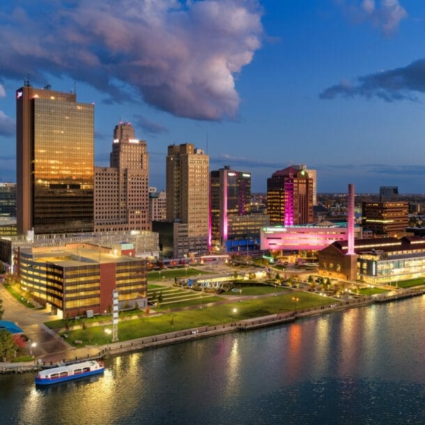Stadtansicht von Toledo bei Abenddämmerung mit beleuchteten Gebäuden und reflektierendem Wasser im Vordergrund