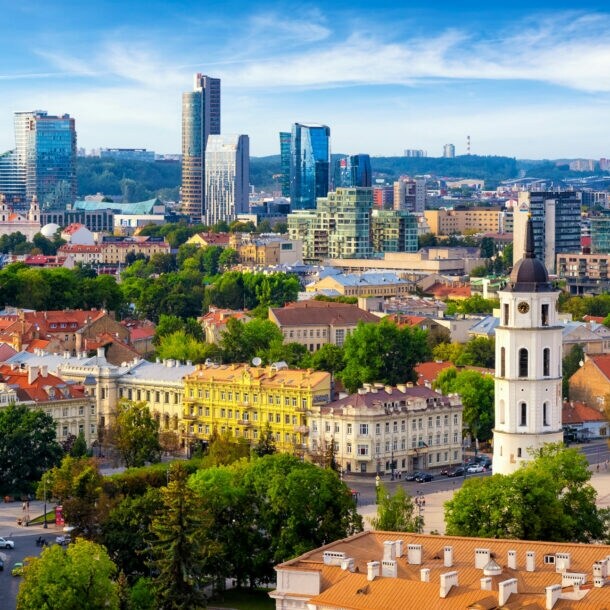 Stadtpanorama von Vilnius mit Kirchturm in Altstadt vor modernen Hochhäusern im Hintergrund.