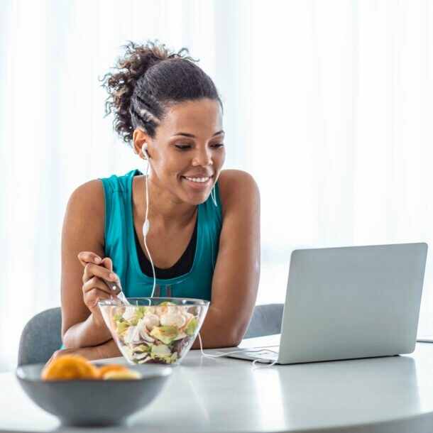 Eine Frau isst einen Salat an ihrem Arbeitsplatz.