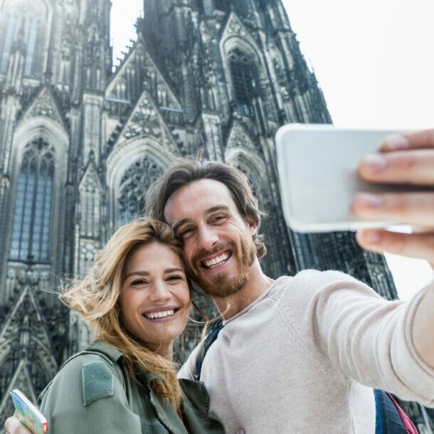 Junges Paar macht Selfie vor dem gotischen Kölner Dom an einem hellen Tag