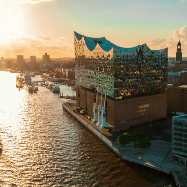 Sonnenuntergang über der Elbphilharmonie in Hamburg mit einem Schiff auf der Elbe und Stadtansicht im Hintergrund.
