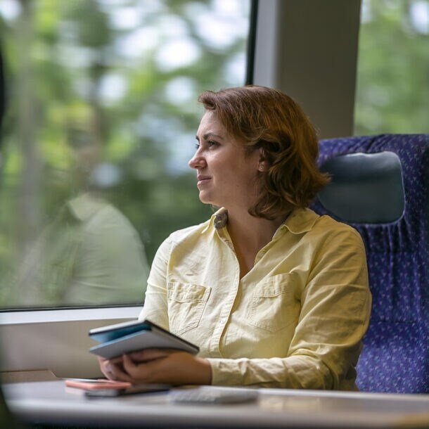 Eine Geschäftsfrau reist klimafreundlich im modernen Zug.