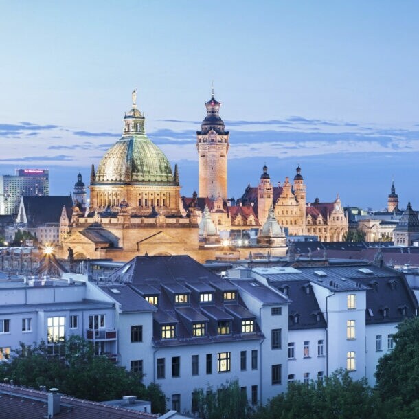 Skyline von Leipzig bei Abenddämmerung mit markanter Kuppel der Nikolaikirche und dem City-Hochhaus im Hintergrund