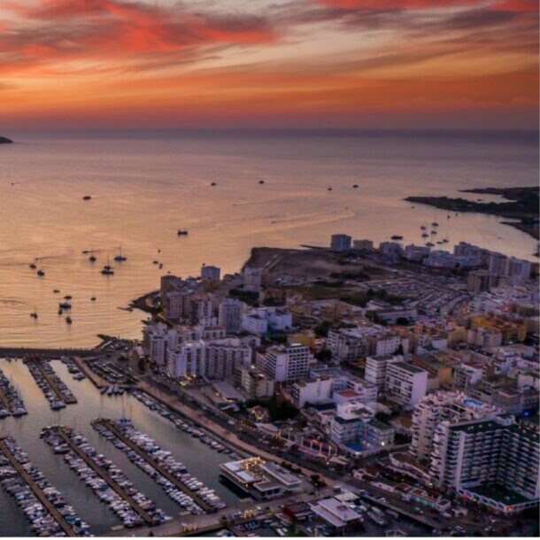Luftaufnahme eines Hafens mit vielen Booten und Yachten bei Sonnenuntergang mit orangefarbenem Himmel