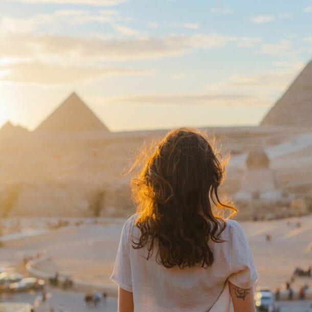 Frau mit lockigem Haar blickt auf die Pyramiden von Gizeh bei Sonnenuntergang