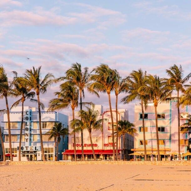 Blick auf die Häuser am Ocean Drive mit Strand und Palmen im Vordergrund.