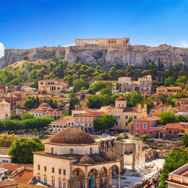 Blick auf die Akropolis von Athen mit blühendem Bougainvillea im Vordergrund und historischen Gebäuden darunter