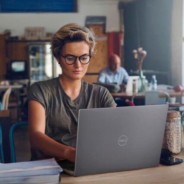 Eine Frau arbeitet in einem Café am Laptop.