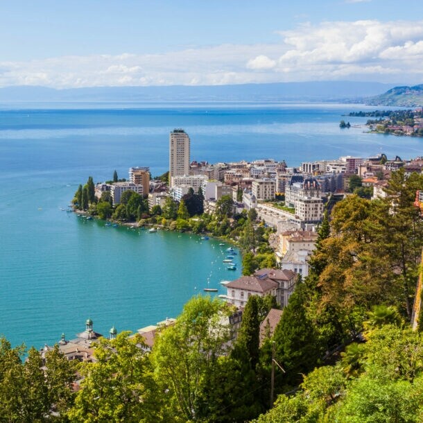 Blick auf den Genfersee mit einem Ausflugsboot, umgeben von Bergen und der Stadt Montreux am Ufer