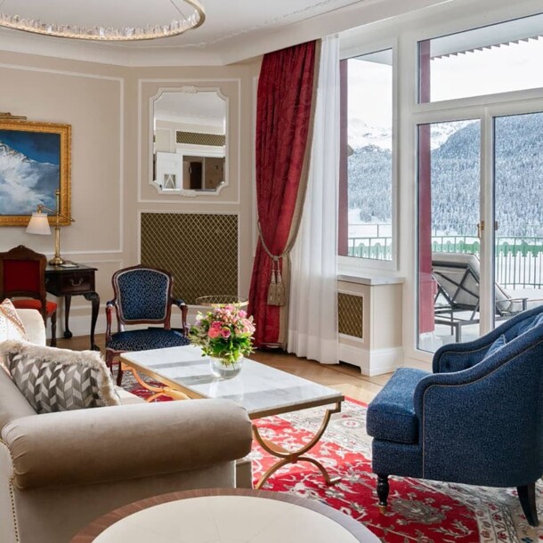Edle, helle Hotelsuite mit Terrasse mit Blick in schneebedeckte Berglandschaft.