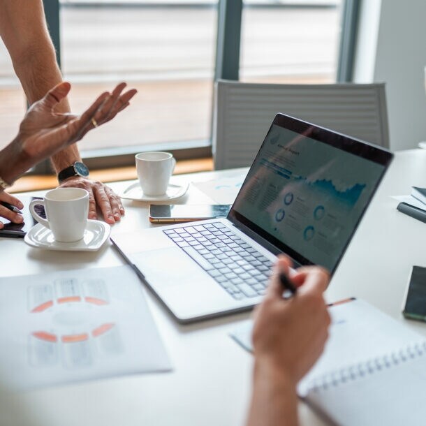 Das Bild zeigt eine Nahaufnahme eines Laptops während einer Besprechung des Buchhaltungsteams.