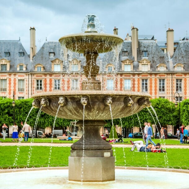 Brunnen mit fließendem Wasser im Place des Vosges, Paris, vor historischen Gebäuden und Bäumen