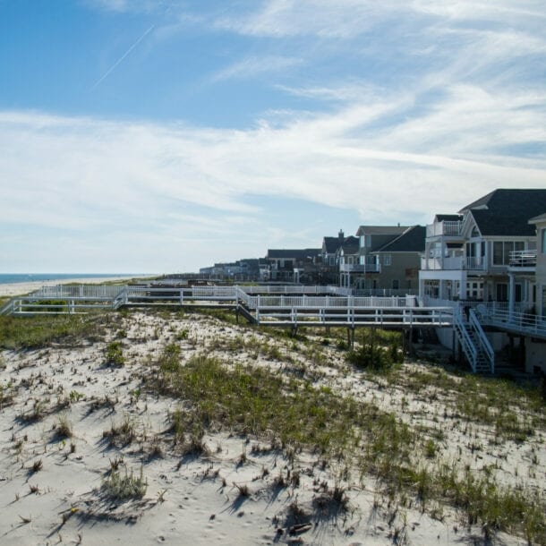 Weg zu einem Sandstrand mit Dünen unter blauem Himmel.