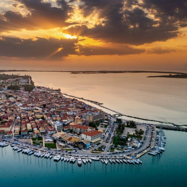 Küstenort mit Hafen von oben bei Sonnenuntergang umgeben von Meer.