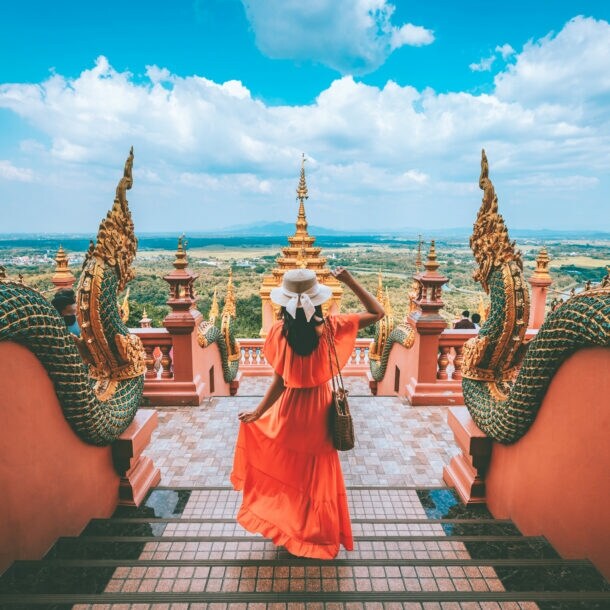 Eine Urlauberin steht in einer Tempelanlage in Thailand