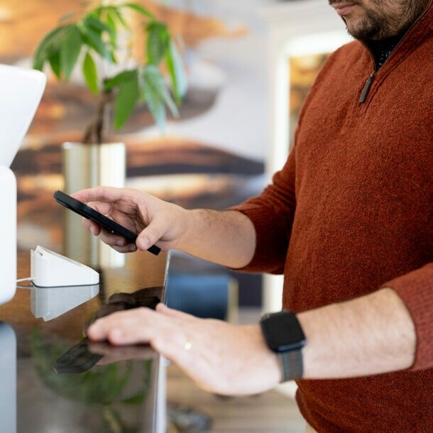 Nahaufnahme eines Mannes, der via Smartphone eine Zahlung in einem Geschäft tätigt.