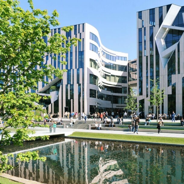Moderne Bürogebäude mit Glasfassaden am Wasserbecken im Kö-Bogen Düsseldorf, Menschen sitzen und gehen auf der Promenade