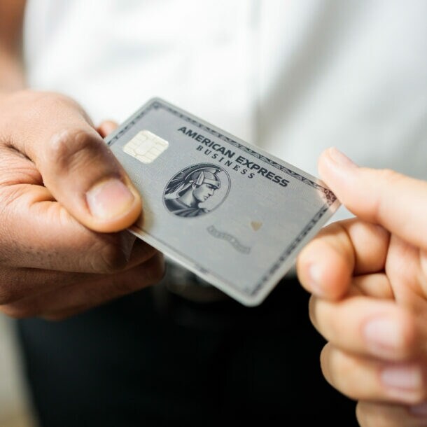 Eine Person übergibt einer anderen eine Business Platinum Card von American Express.